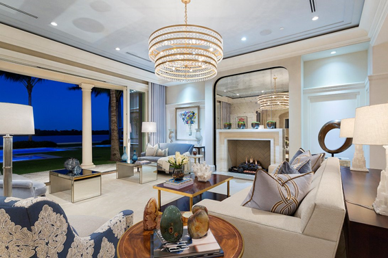 Contemporary designed living room with a large chandelier, a fireplace, and a lakefront view.