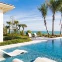 Lounge chairs partially immersed in a pool with an ocean view.