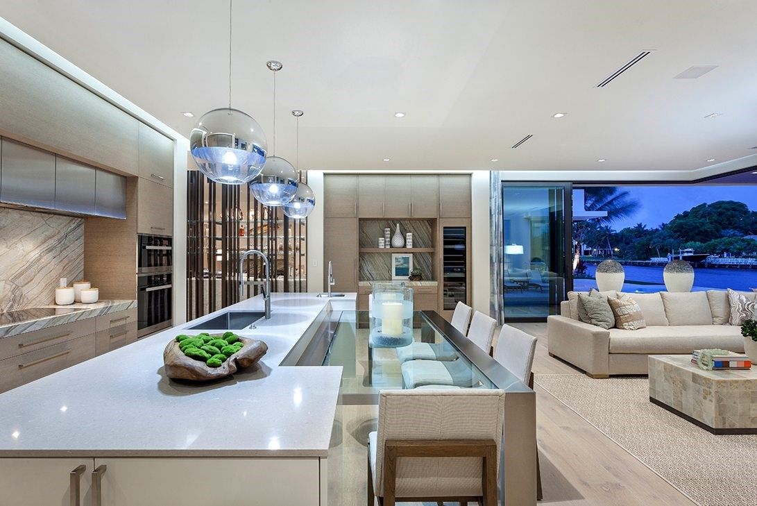Luxurious kitchen with lighting fixtures above a lengthy island with a dining table extension.