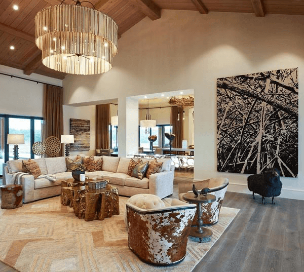 A luxurious ranch with many different textured accessories, such as chairs, paintings, and a chandelier.