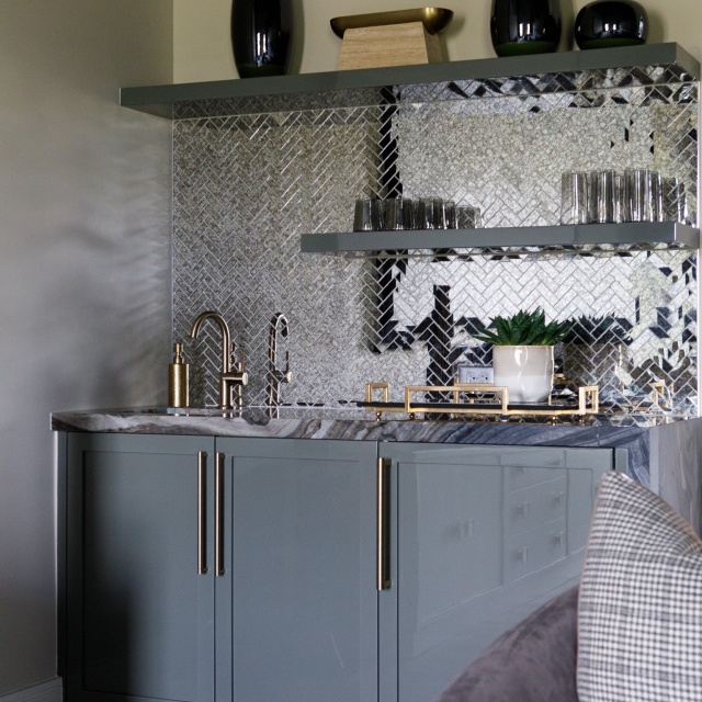 Mix and match bold materials to make a statement 🖤 This walk-up bar features an antique mirror tile backsplash and a stunning silver wave marble waterfall countertop. #walkupbar #homebar #homebarstyle #interiordesign #luxuryhomes