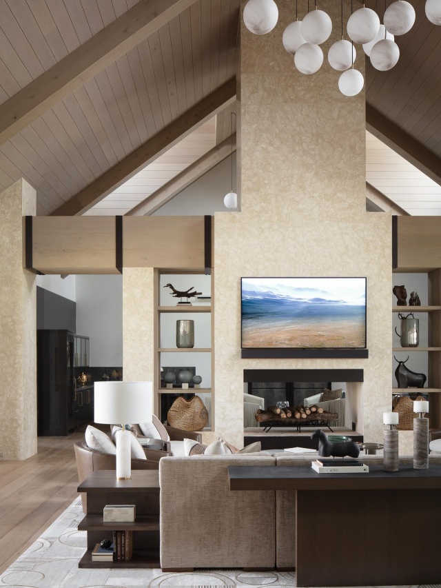 The living room’s double-sided fireplace—shared with an adjacent club room—generates a sculptural centerpiece, lending warmth and ambiance while maintaining an open-concept layout. A sizable sofa from Lazar Industries and cozy Century club chairs establish a conversation area around a trio of marble-topped Palecek cocktail tables. @floridadesign @jessglynnphoto #featured #floridadesign #pinecreekranch #modernranch #interiordesign #livingroom